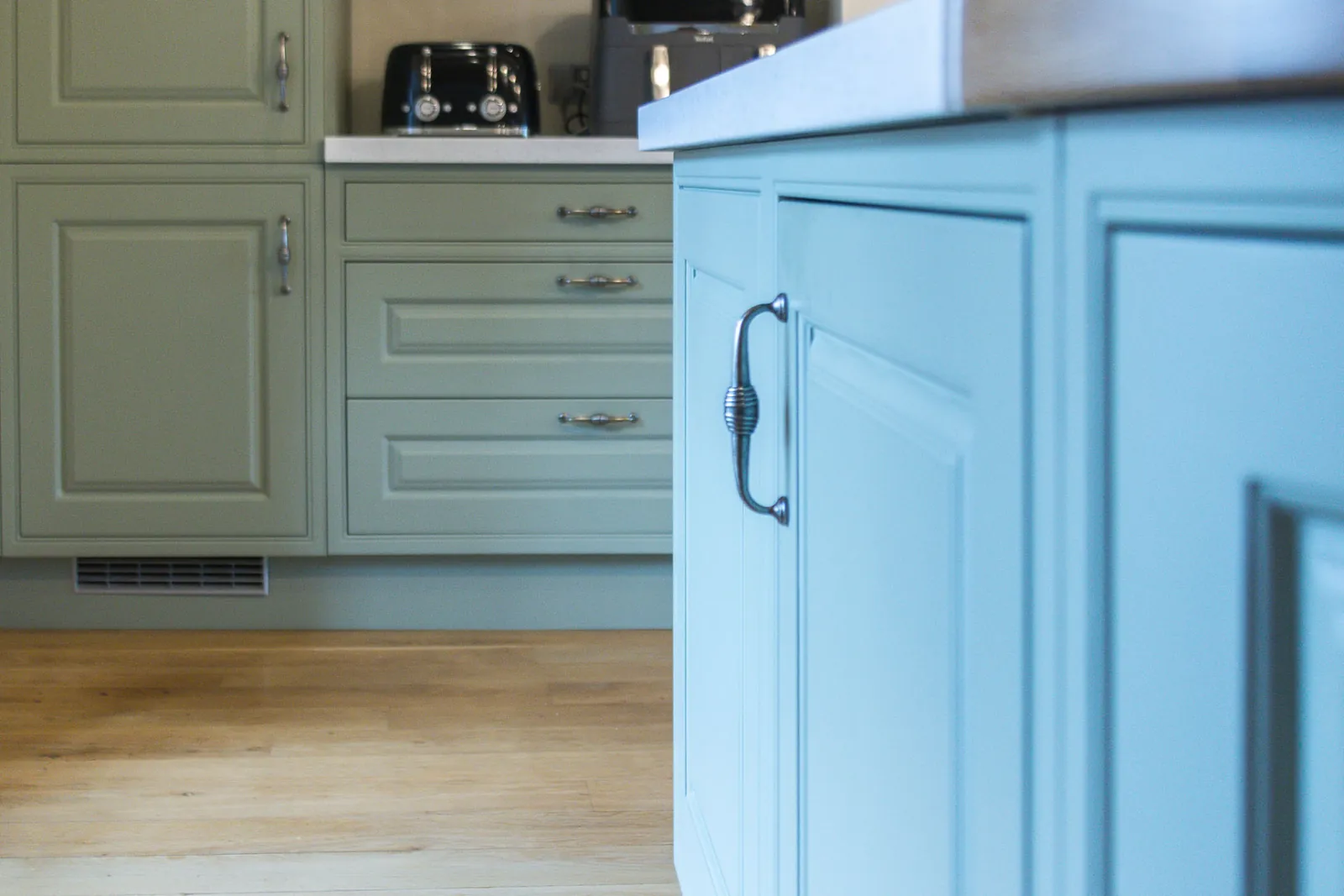 Close view of the sprayed green island next to sage green cupboards and drawers, in Bradford on Avon