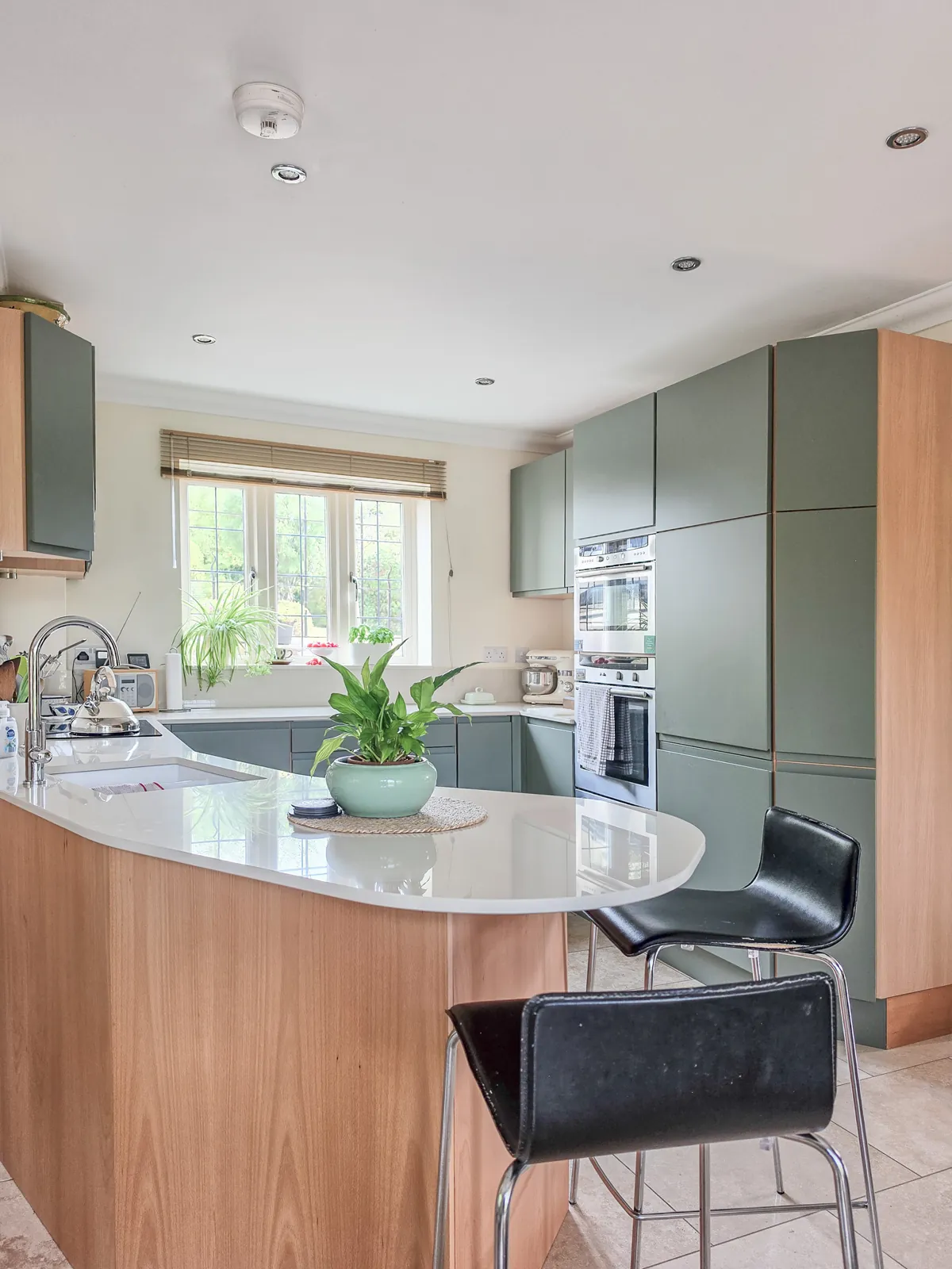 Finished Brinkworth kitchen with green replacement doors and a curved breakfast bar