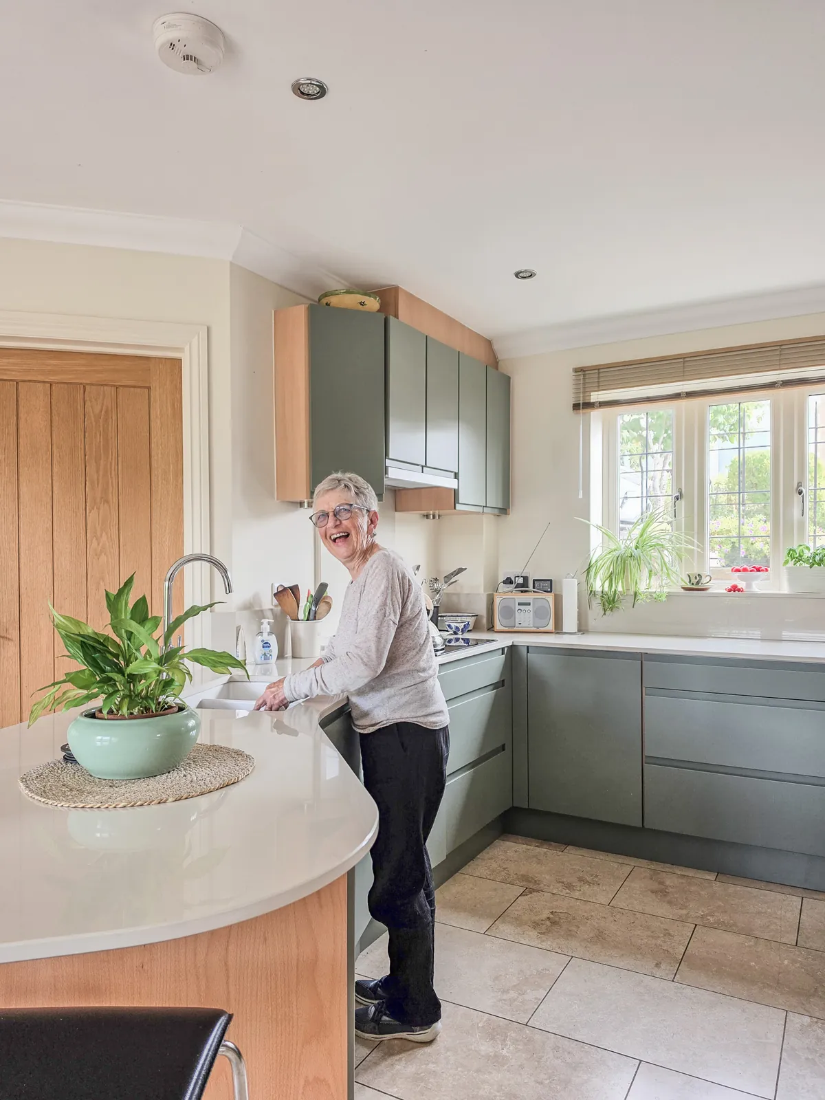 Finished Brinkworth kitchen viewed across the breakfast bar, with a person standing beside it