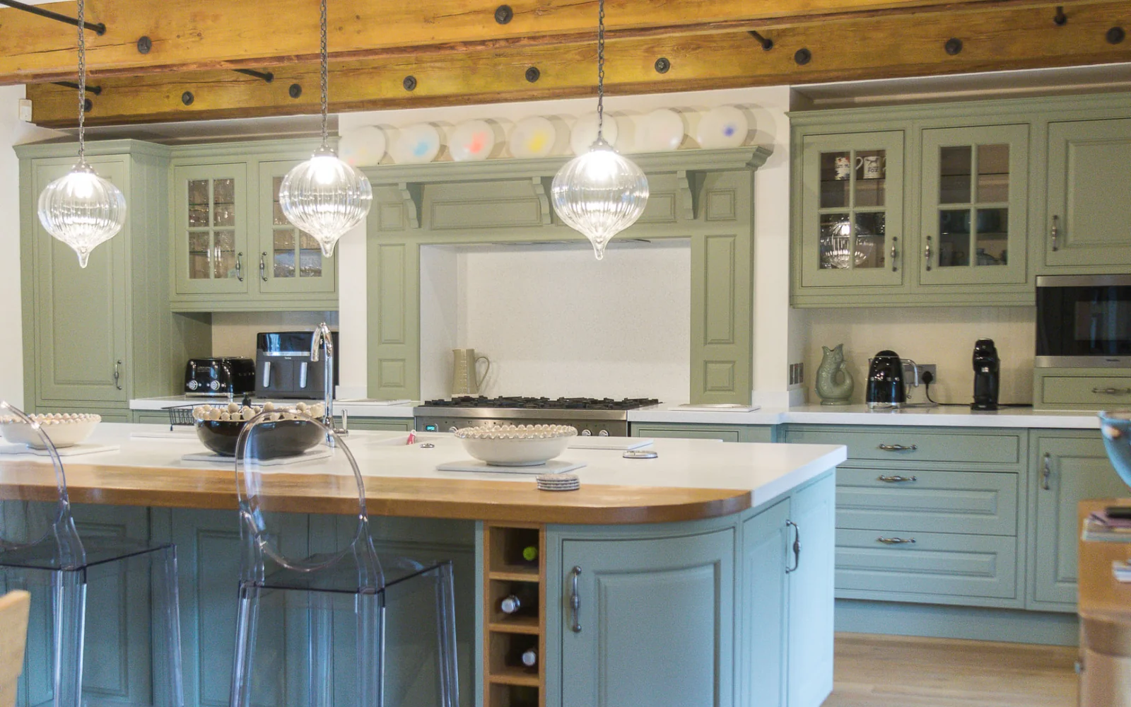 A sage green hand-finished kitchen with a painted island and timber worktop in a Wiltshire home