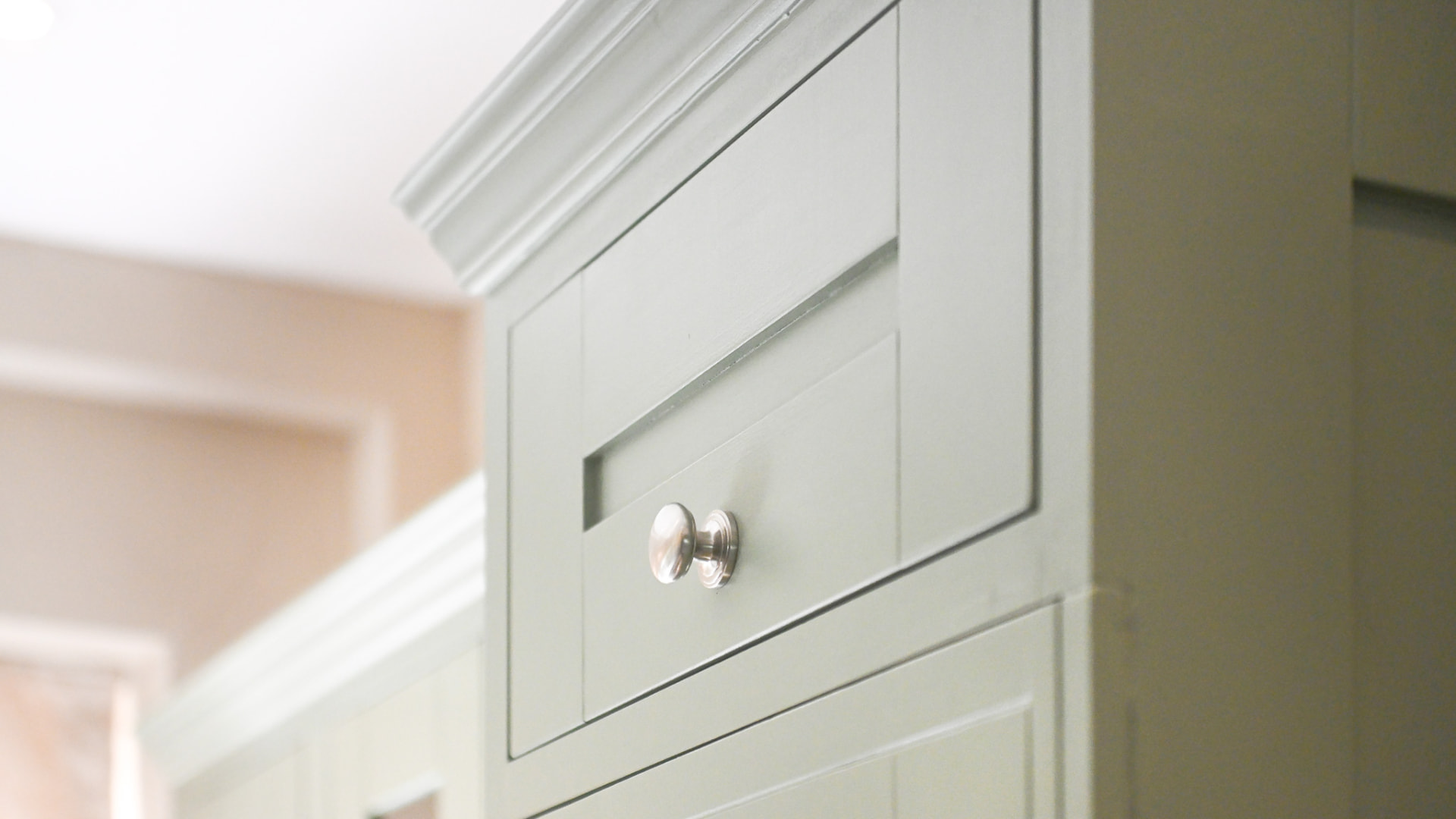 Close-up of the finished green high cabinetry, with aligned panel detailing, upper mouldings and a metal knob