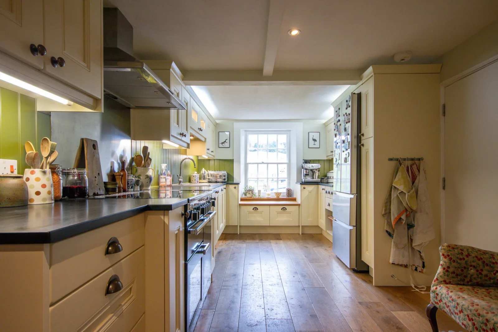 Cream painted shaker kitchen in a Wiltshire cottage with dark work surfaces, a range cooker and an oak floor after a refresh