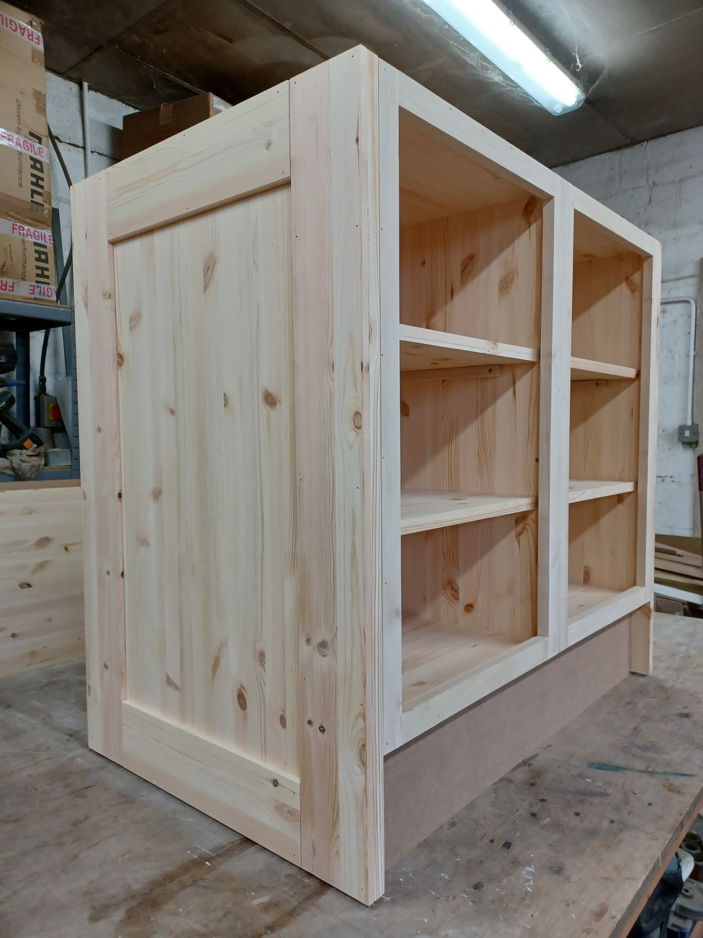 Unfinished bespoke cabinetry on a workshop bench, showing its timber construction and open compartments