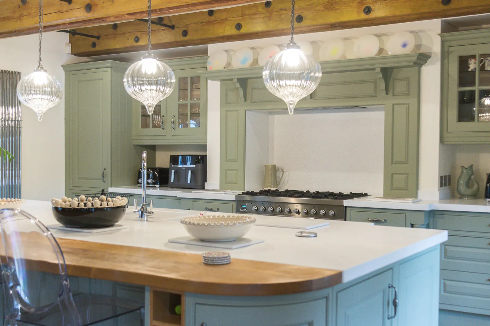 Sprayed sage green wall units and a green island with a quartz and timber worktop, in Bradford on Avon
