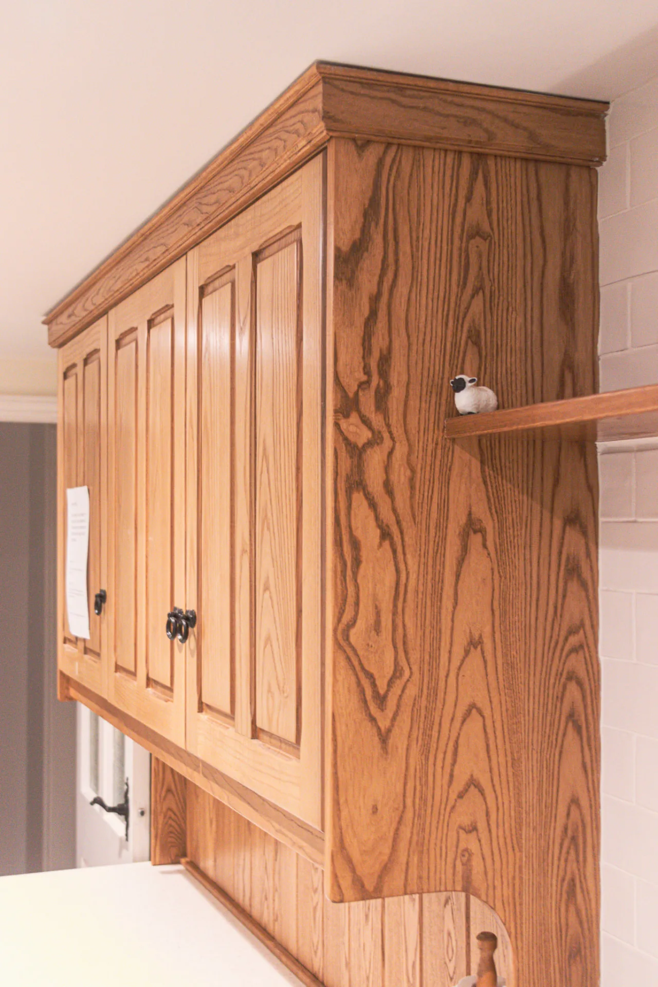 Bespoke solid oak wall cabinet with panelled doors, crown moulding and a small shelf