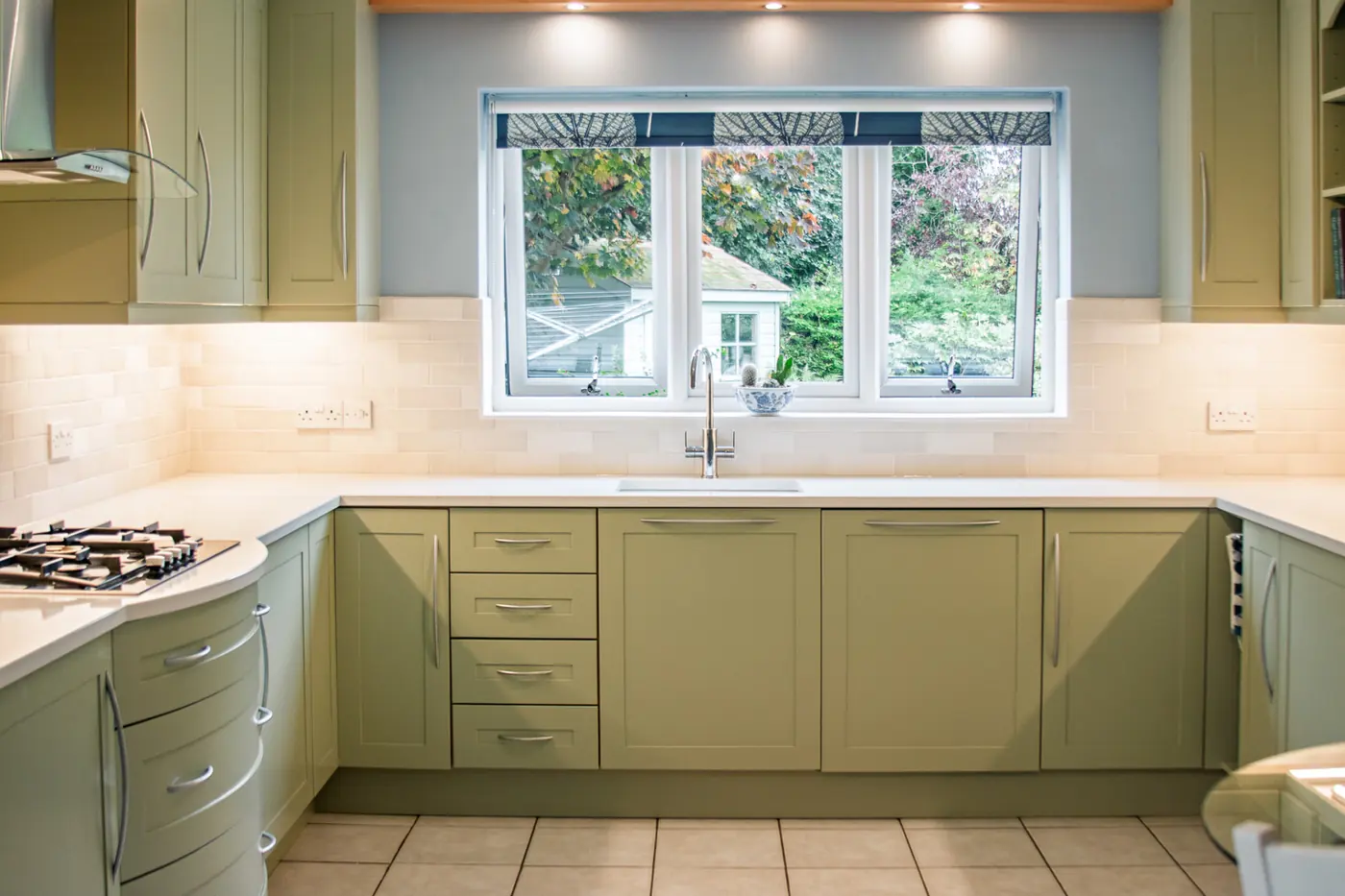 Refreshed sage green shaker kitchen with white quartz worktops and a garden window