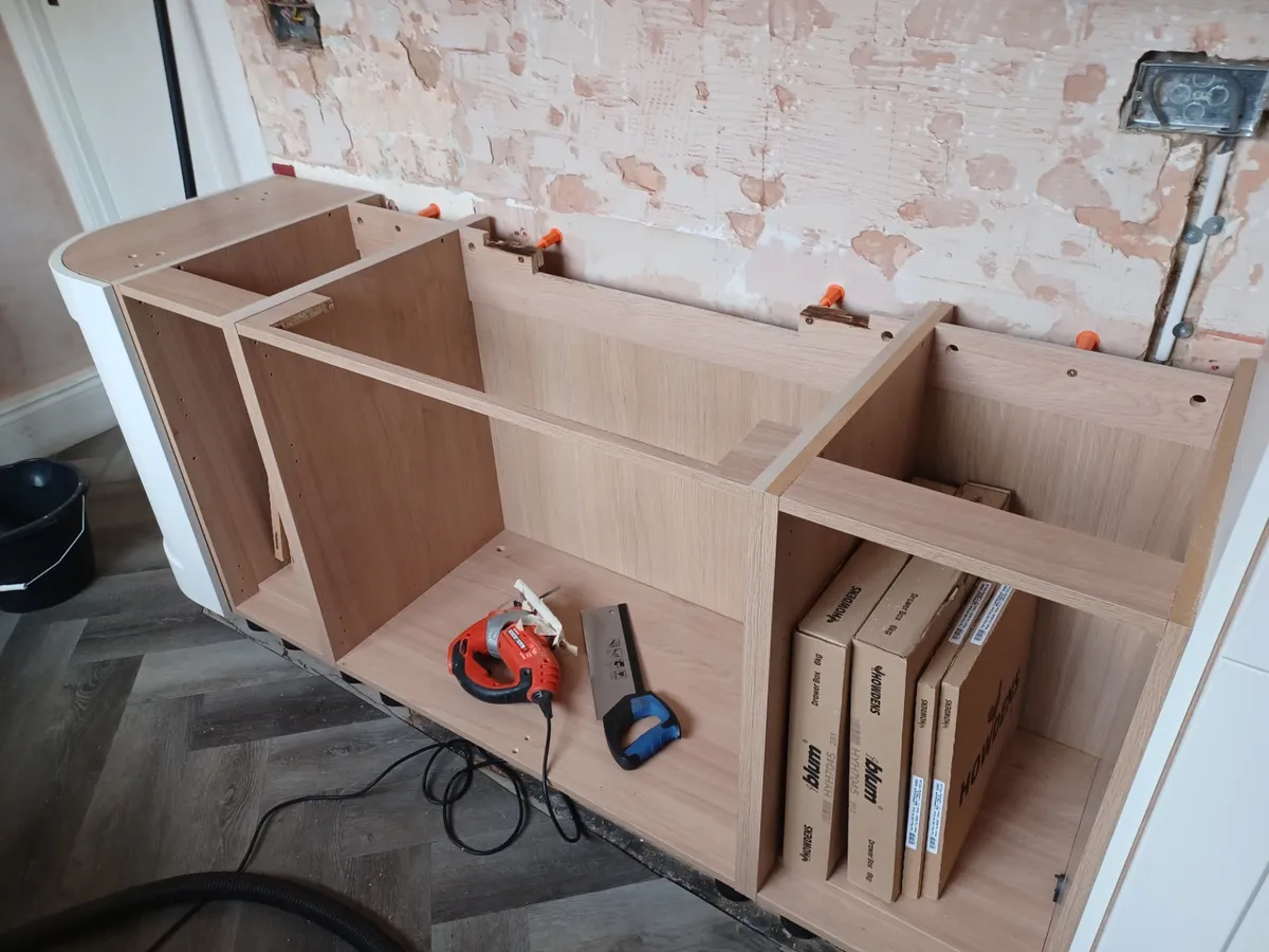 New cabinet carcasses and drawer boxes part-way through a kitchen update, with bare plaster and exposed sockets behind