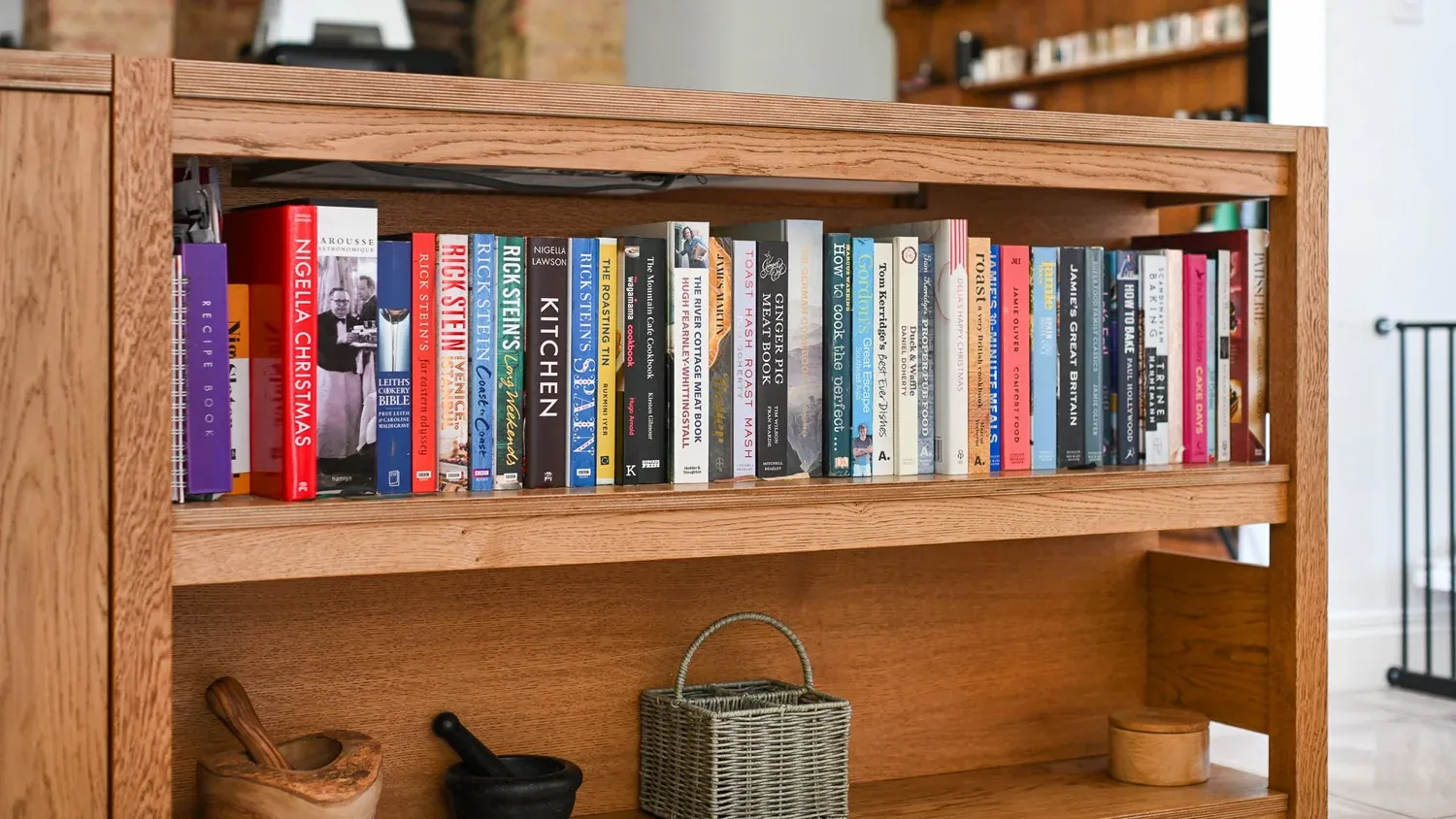 Open oak shelving holding books and kitchen pieces