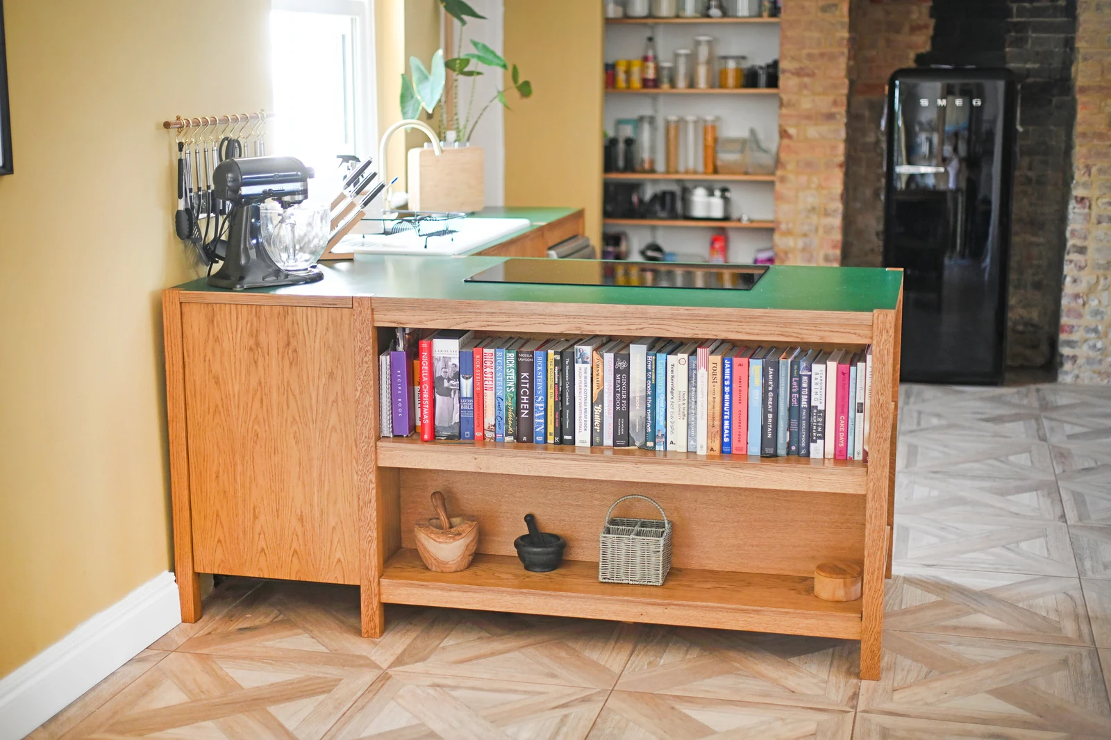The Melksham bespoke kitchen island seen from the cookbook side, with its green worktop and integrated induction hob