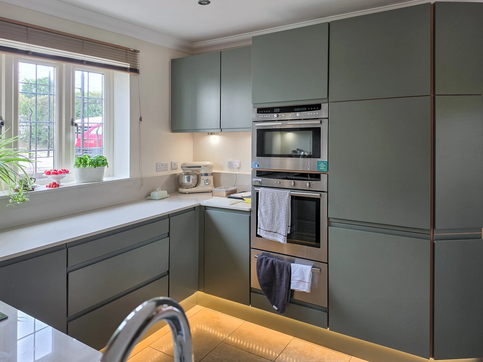 Another view across the refreshed Brinkworth kitchen, with the chrome tap in the foreground, the corner run and the tall oven housing lit by the new LED lighting