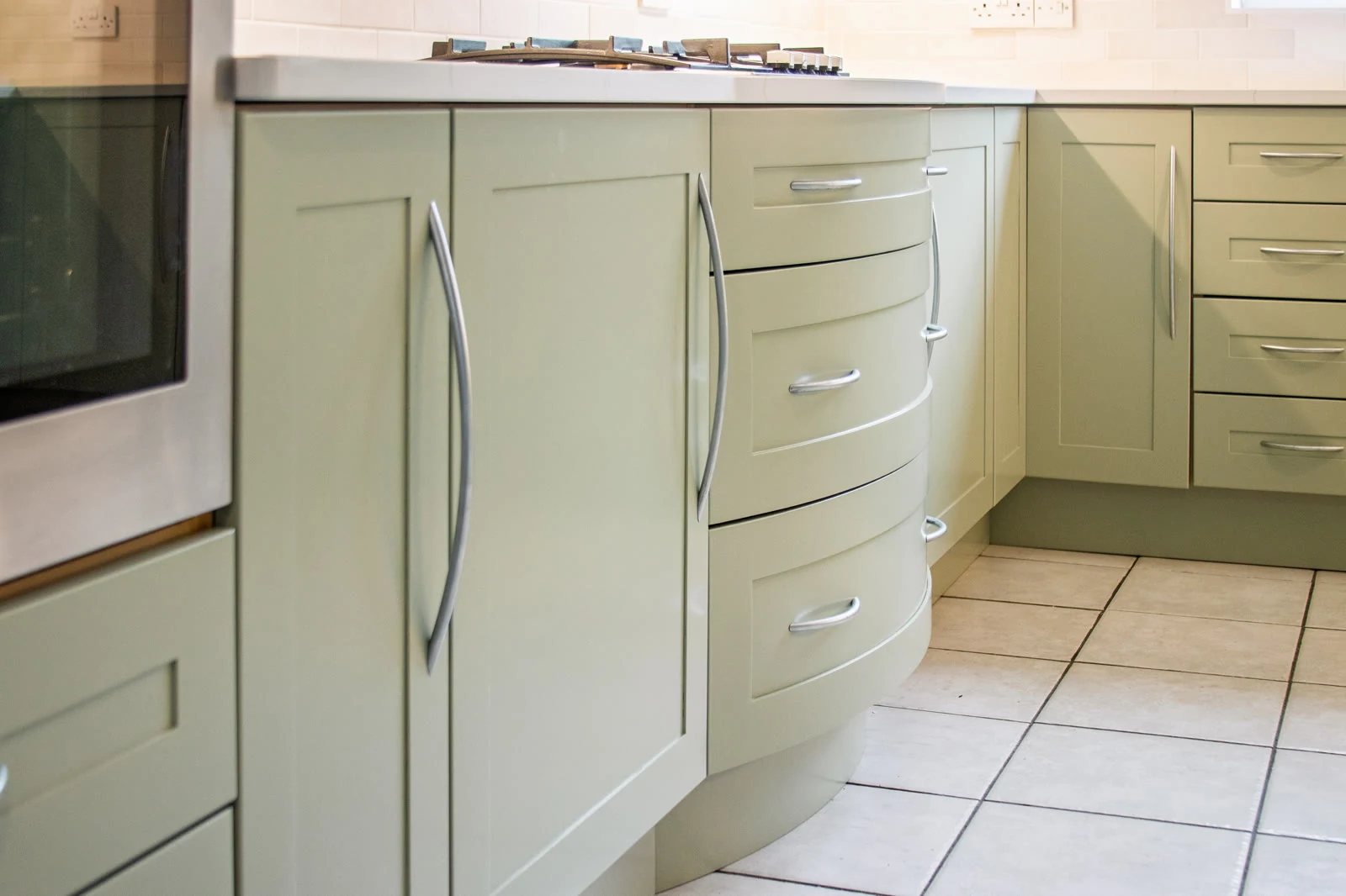 Hob run in the Highworth kitchen, with the original oven, gas hob on a lightly-veined quartz worktop, and the original curved drawer fronts sprayed in Farrow & Ball Vert de Terre