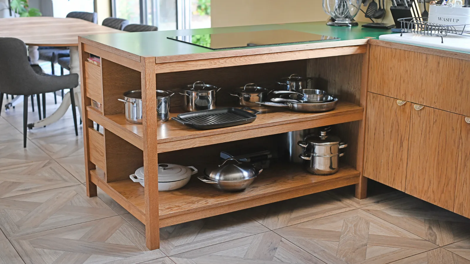 Open shelving built into the bespoke kitchen island in Melksham, used for cookbooks and everyday items.