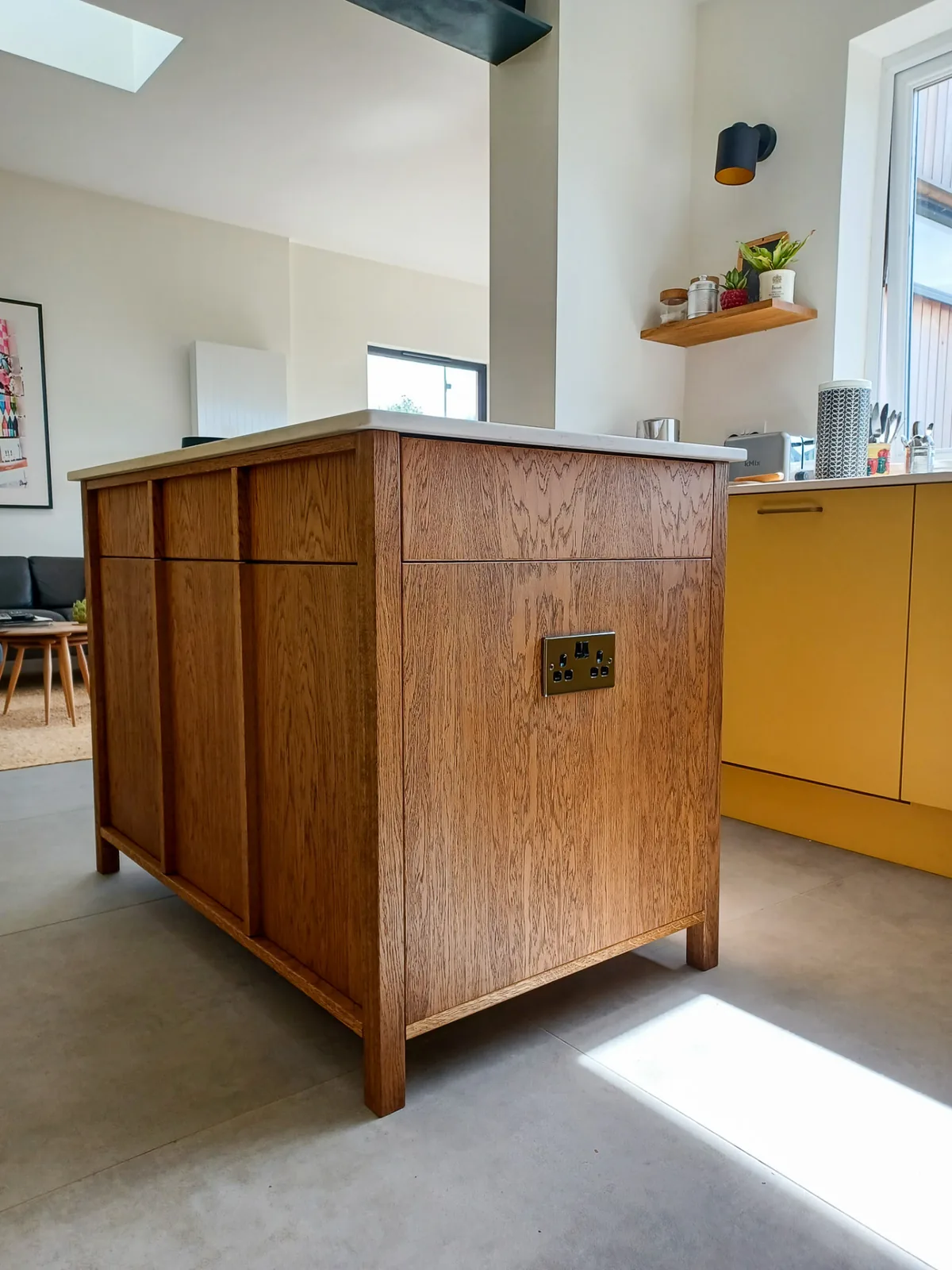 Oak kitchen island with framed timber panels, a white worktop and an integrated socket