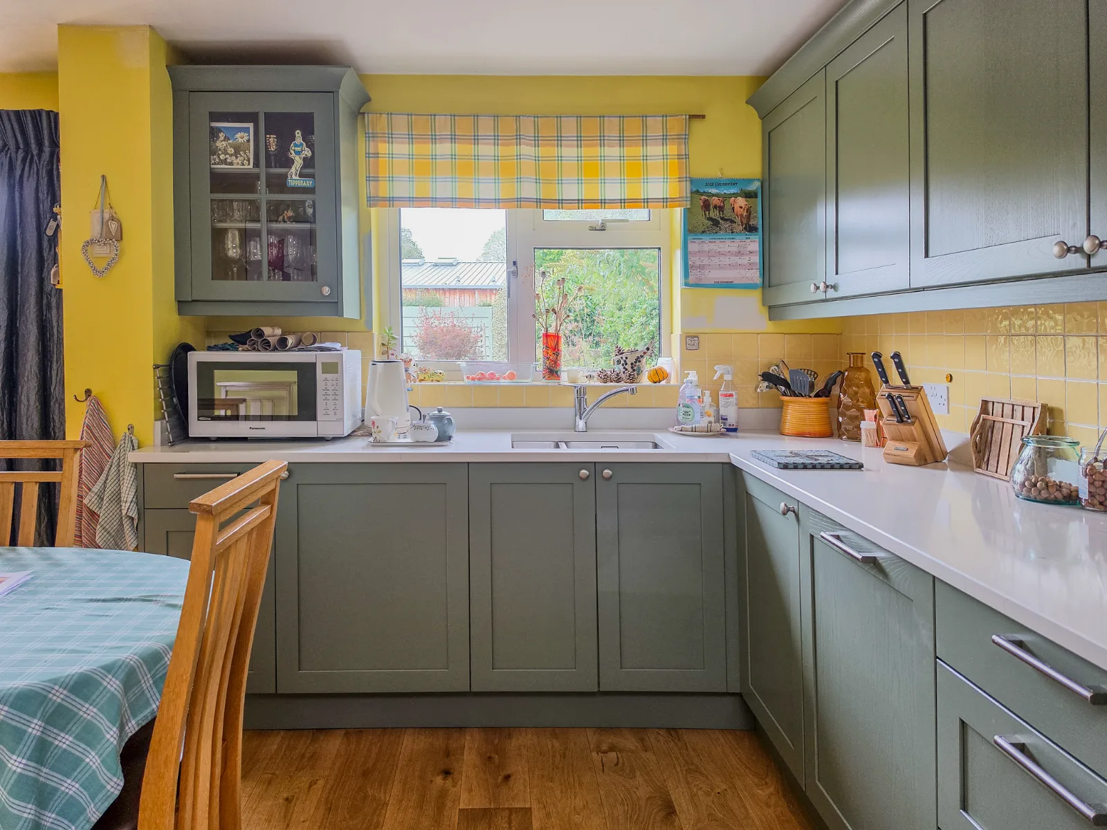 A finished green kitchen with white quartz worktops.