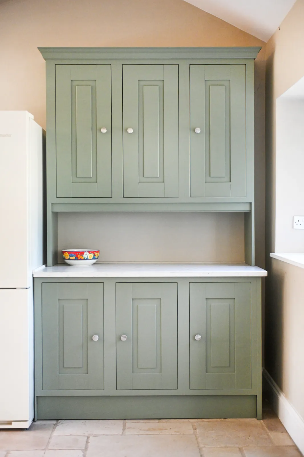 A bespoke green dresser with cupboards above and below