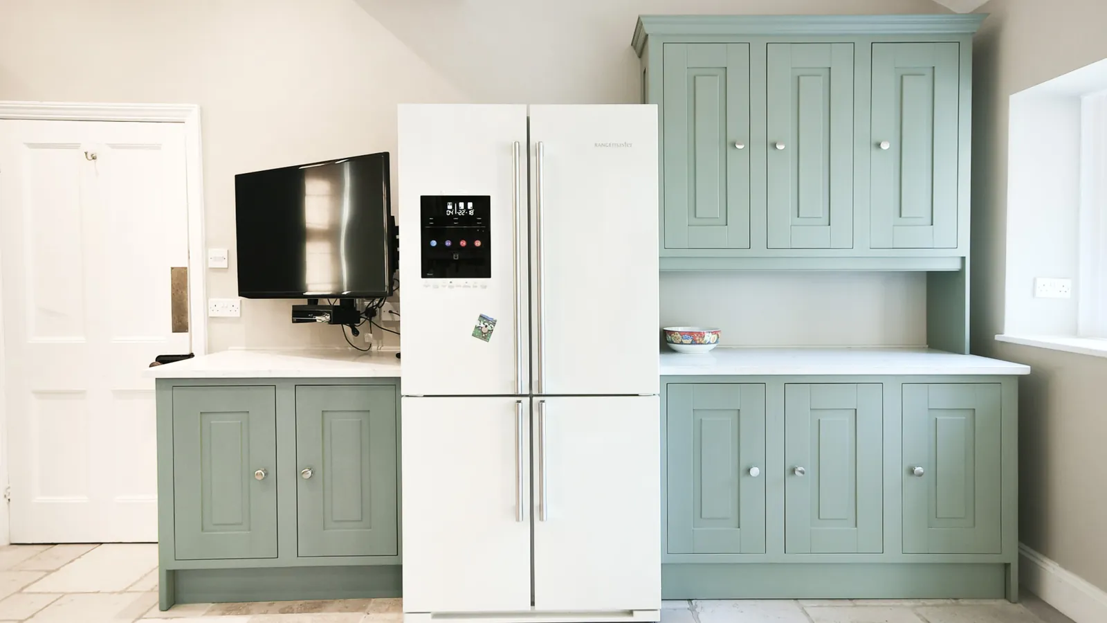 Green base cabinet and dresser either side of a tall fridge