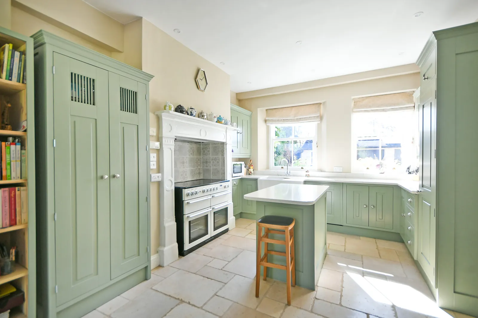 Wide view of the finished green kitchen with bookcase, larder and island