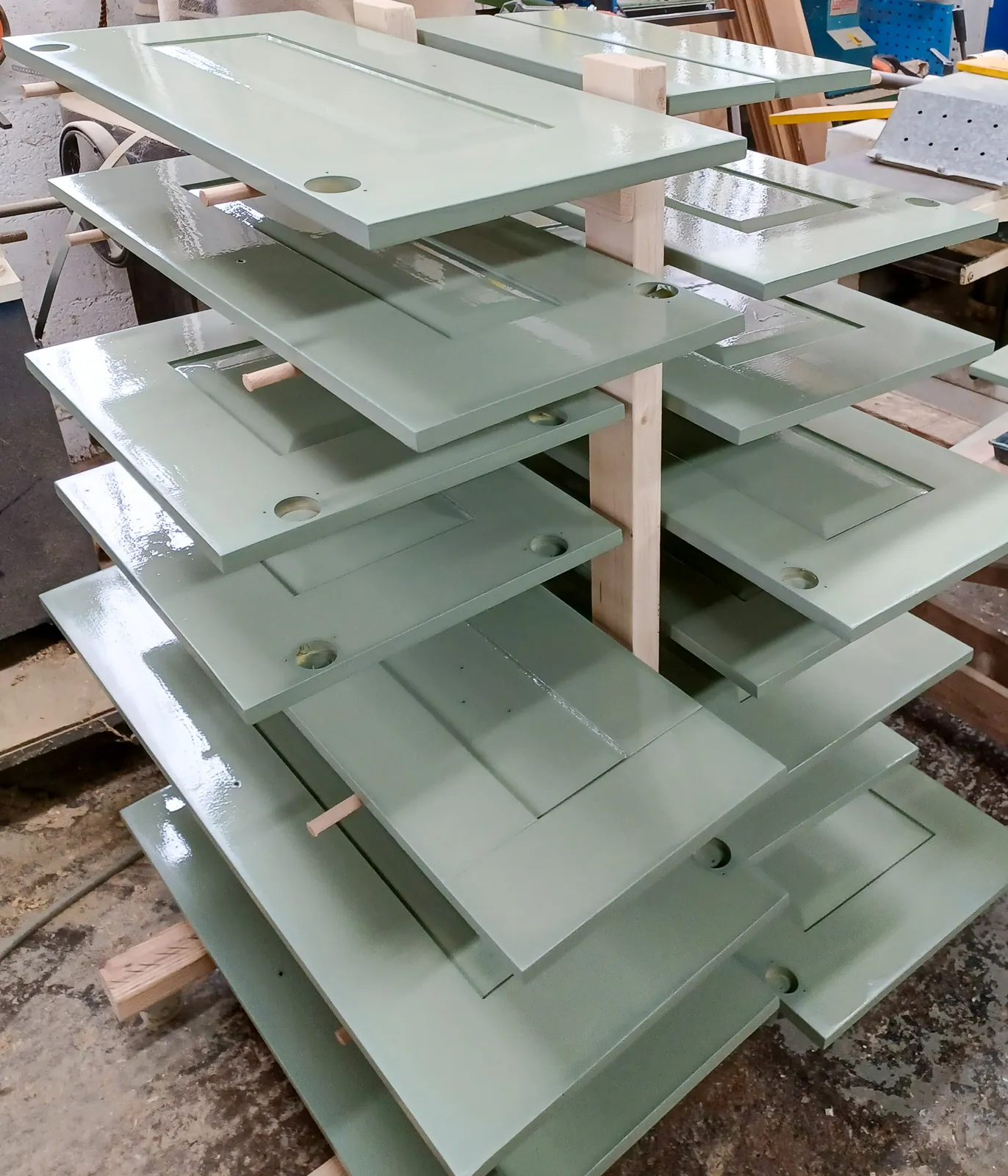 Sprayed green kitchen doors drying on a rack in the workshop