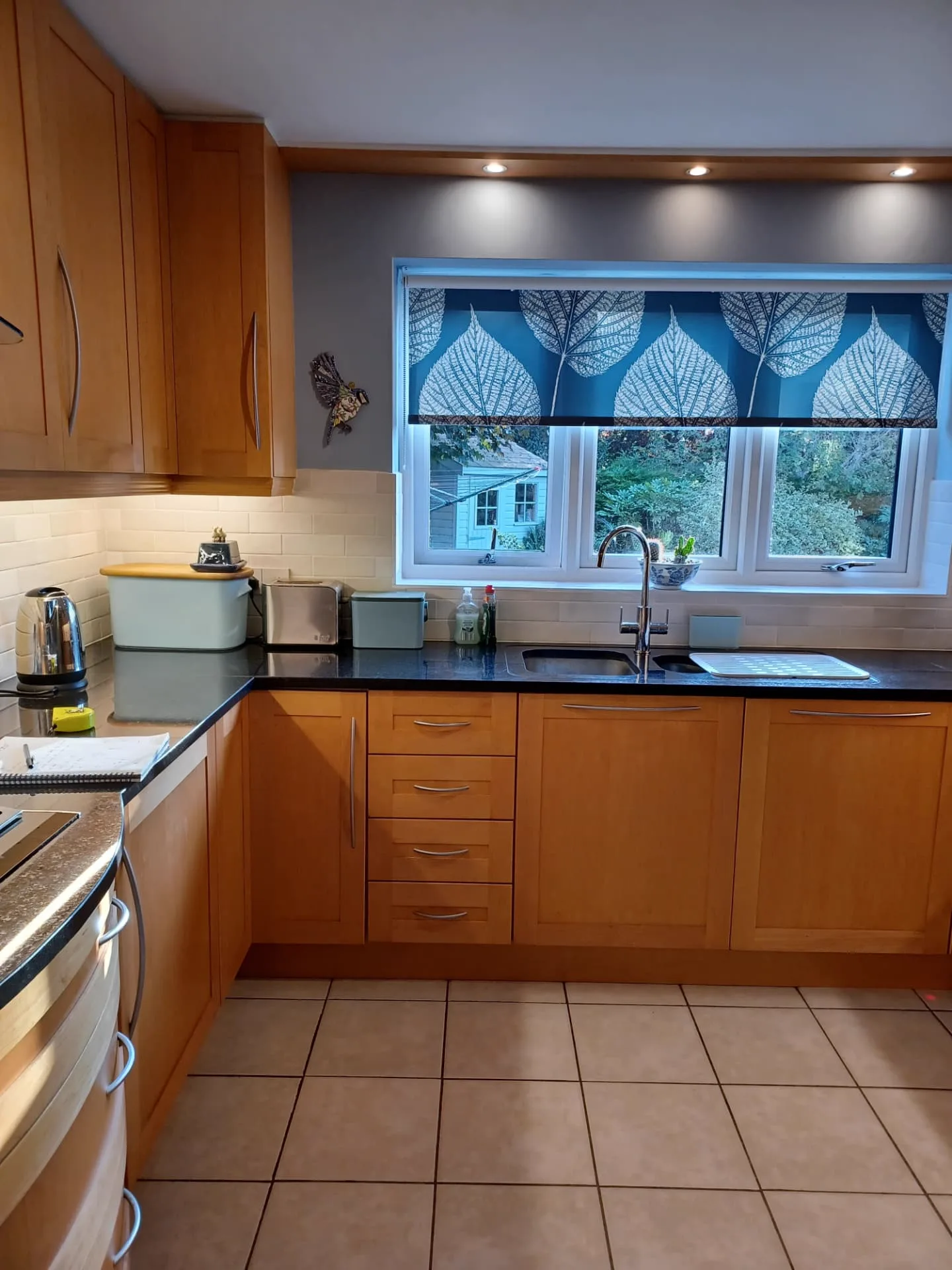The kitchen before, with oak cabinetry and dark speckled granite worktops around the sink run